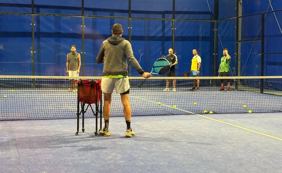 Istruttore di padel durante una lezione di gruppo su campo coperto